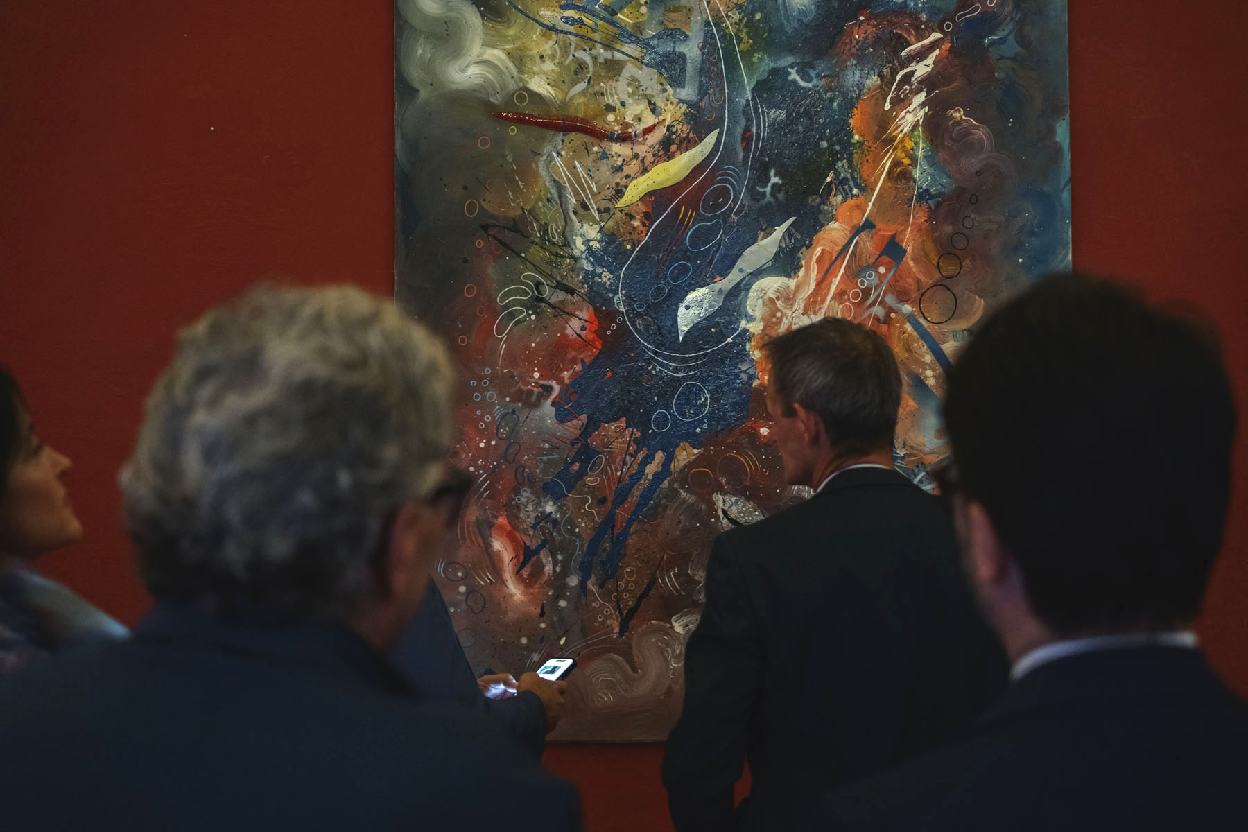 Visitors standing before a work in the SOGLIE exhibition